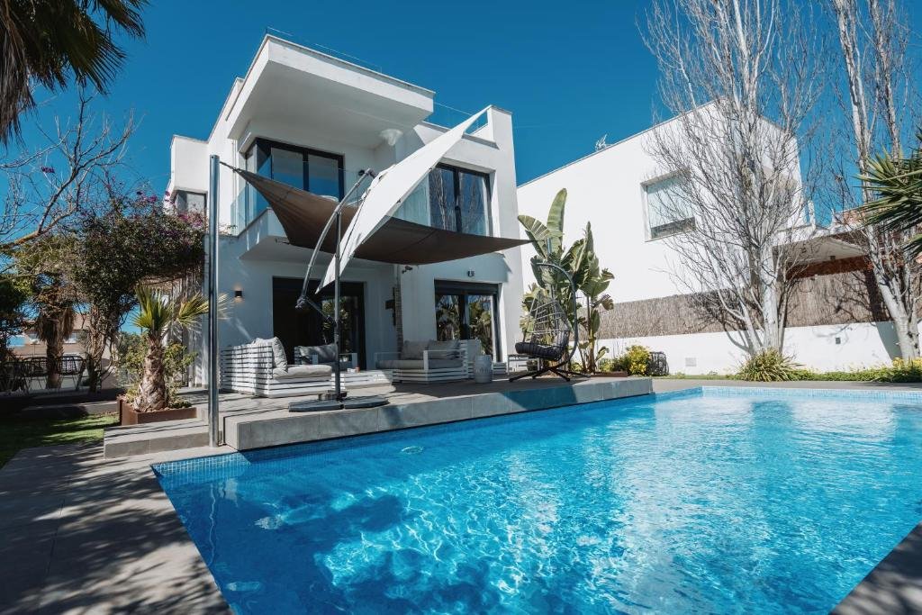 View of the house entrance where you can appreciate its architecture, the pool in front and the garden in the background - Villa Horizont Dreams